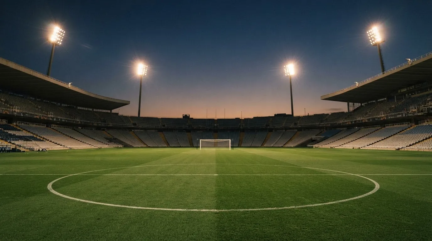 An empty football stadium with floodlight masts at dusk