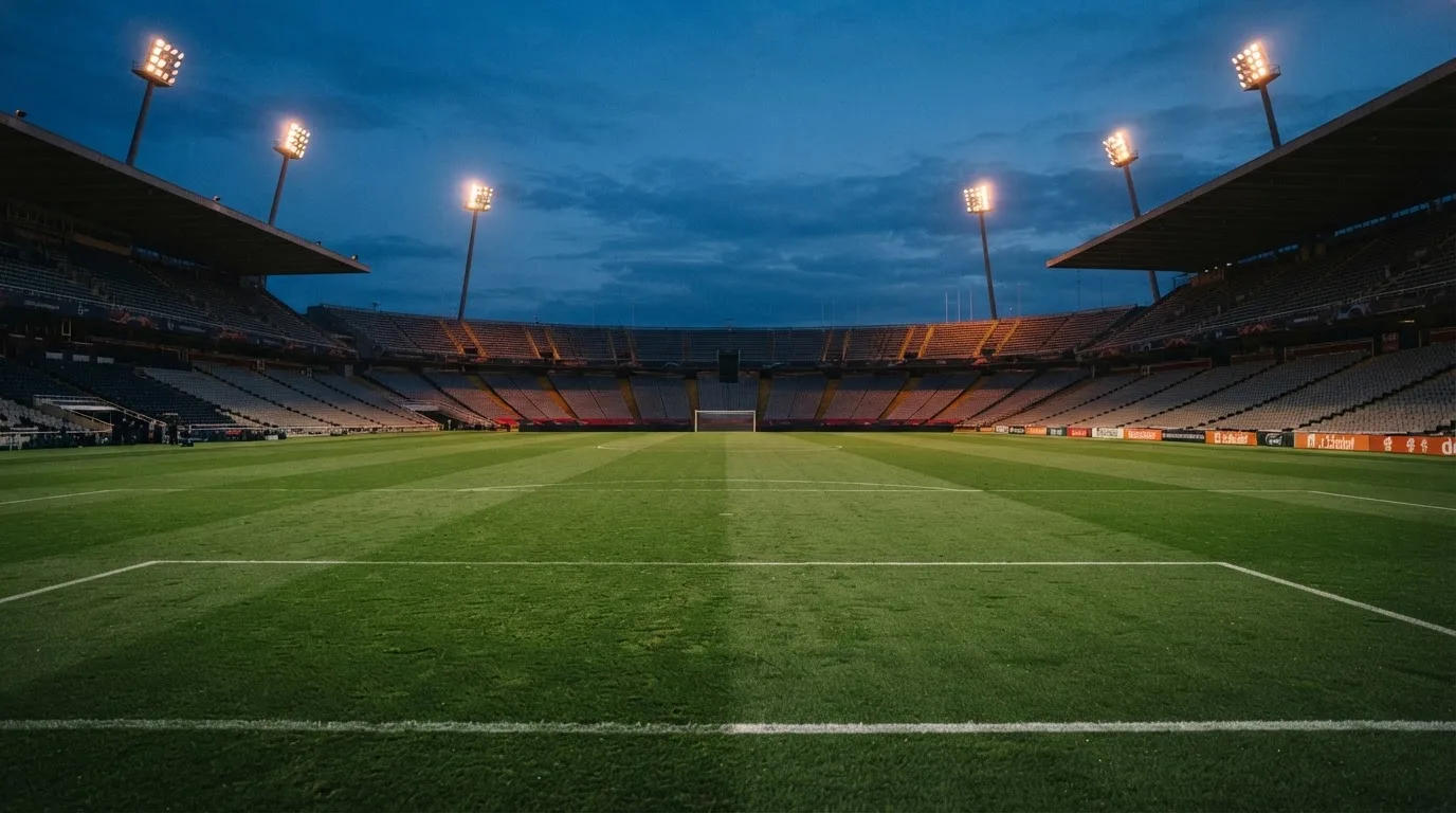 An empty football stadium with floodlight masts at dusk