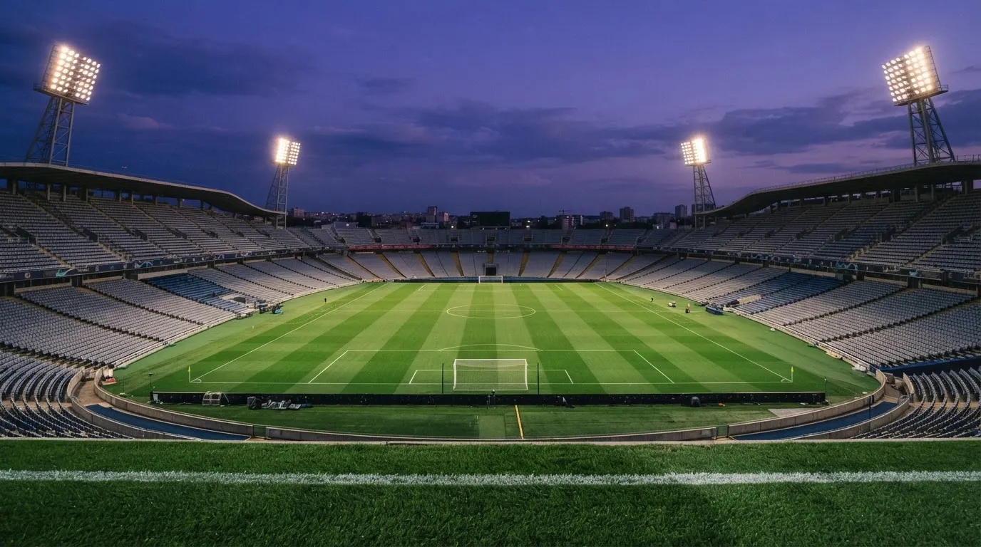 An empty football stadium with floodlight masts at dusk