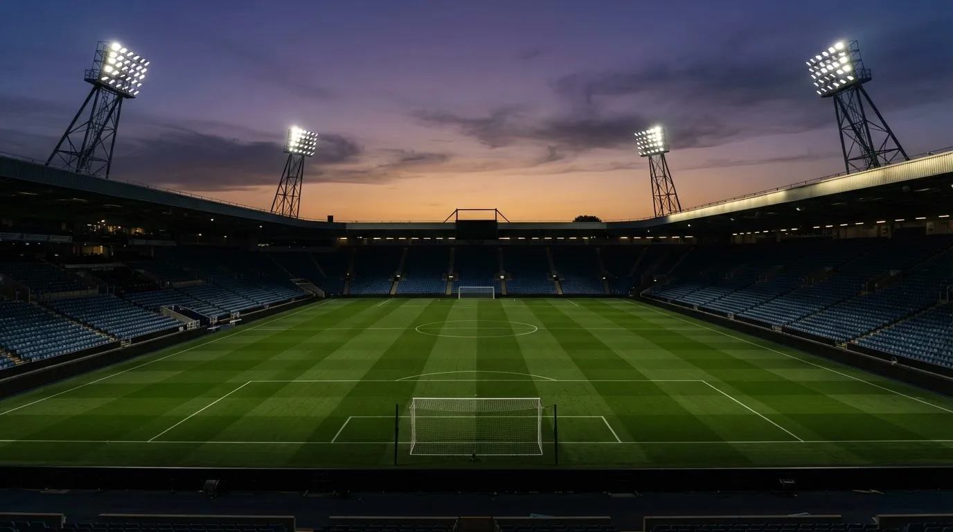 An empty football stadium with floodlight masts at dusk