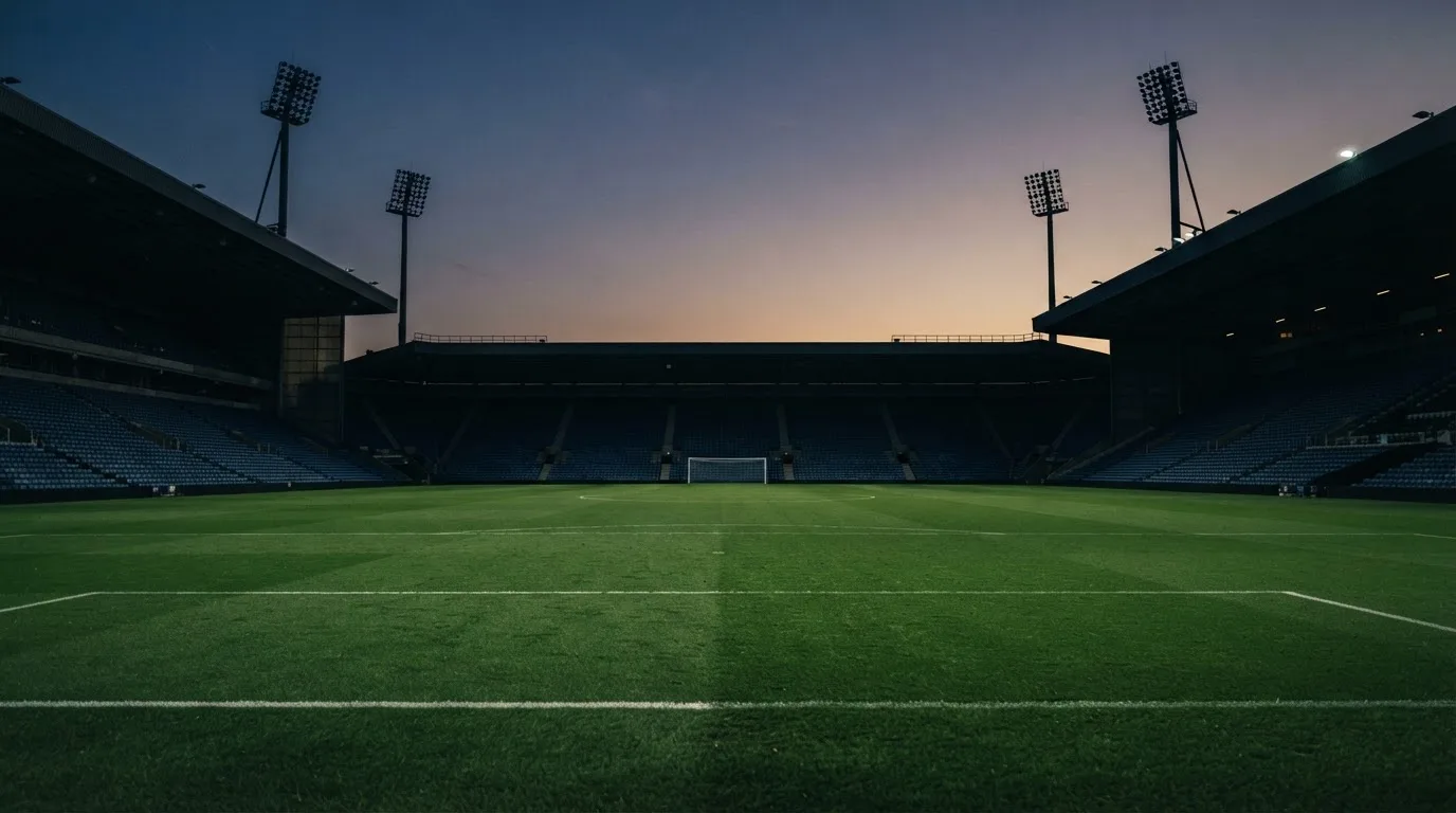 An empty football stadium with floodlight masts at dusk