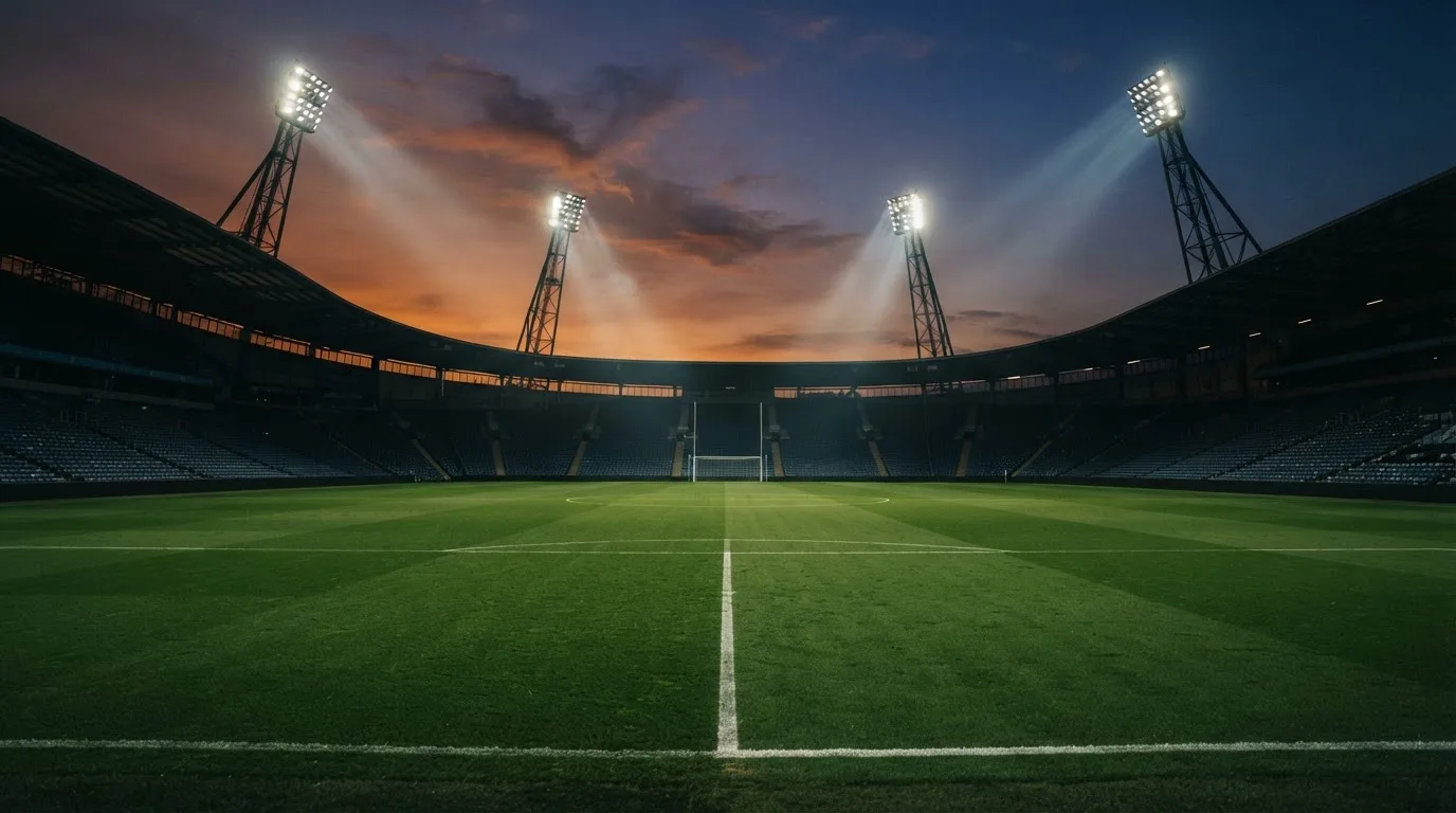An empty football stadium with floodlight masts at dusk