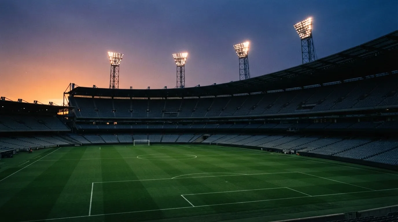 An empty football stadium with floodlight masts at dusk