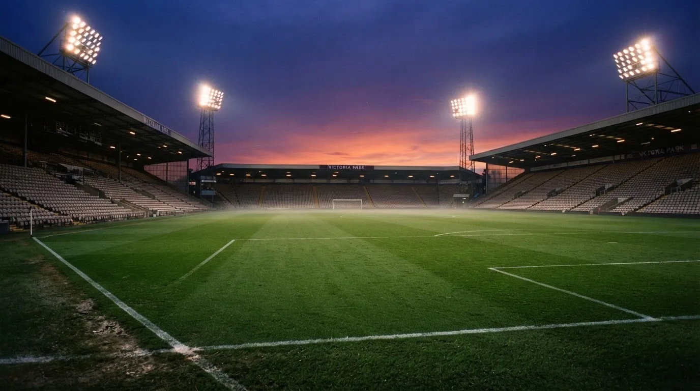 An empty football stadium with floodlight masts at dusk