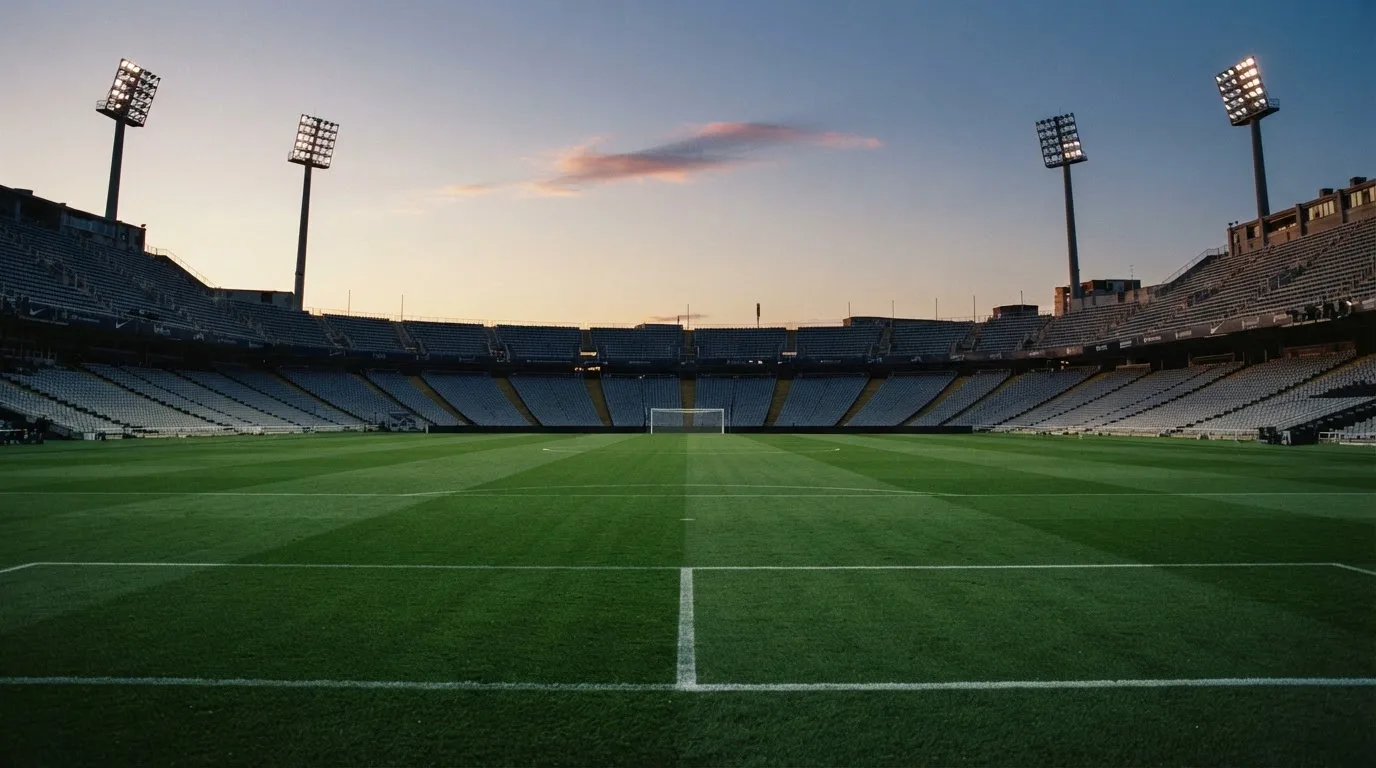 An empty football stadium with floodlight masts at dusk