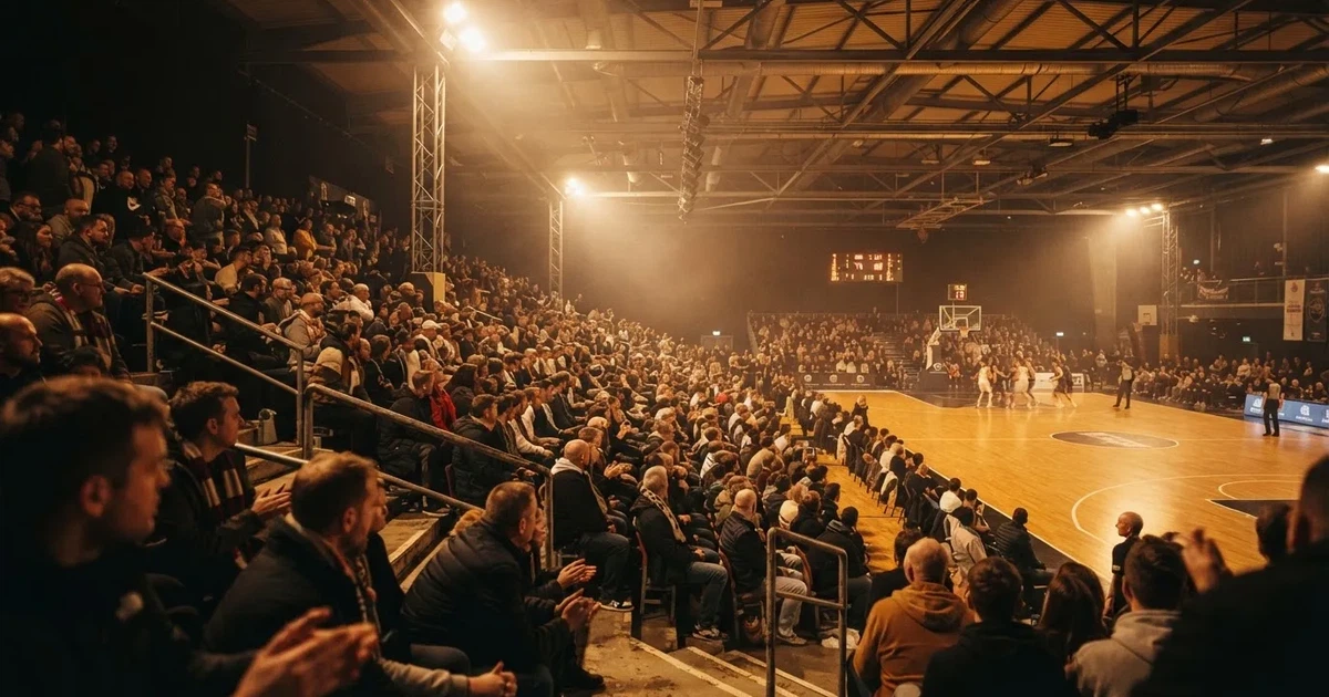 A packed sports hall under floodlights photographed from a long way off
