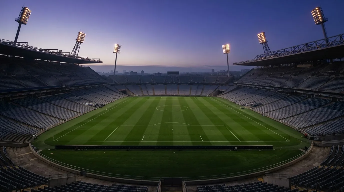 An empty football stadium with floodlight masts at dusk