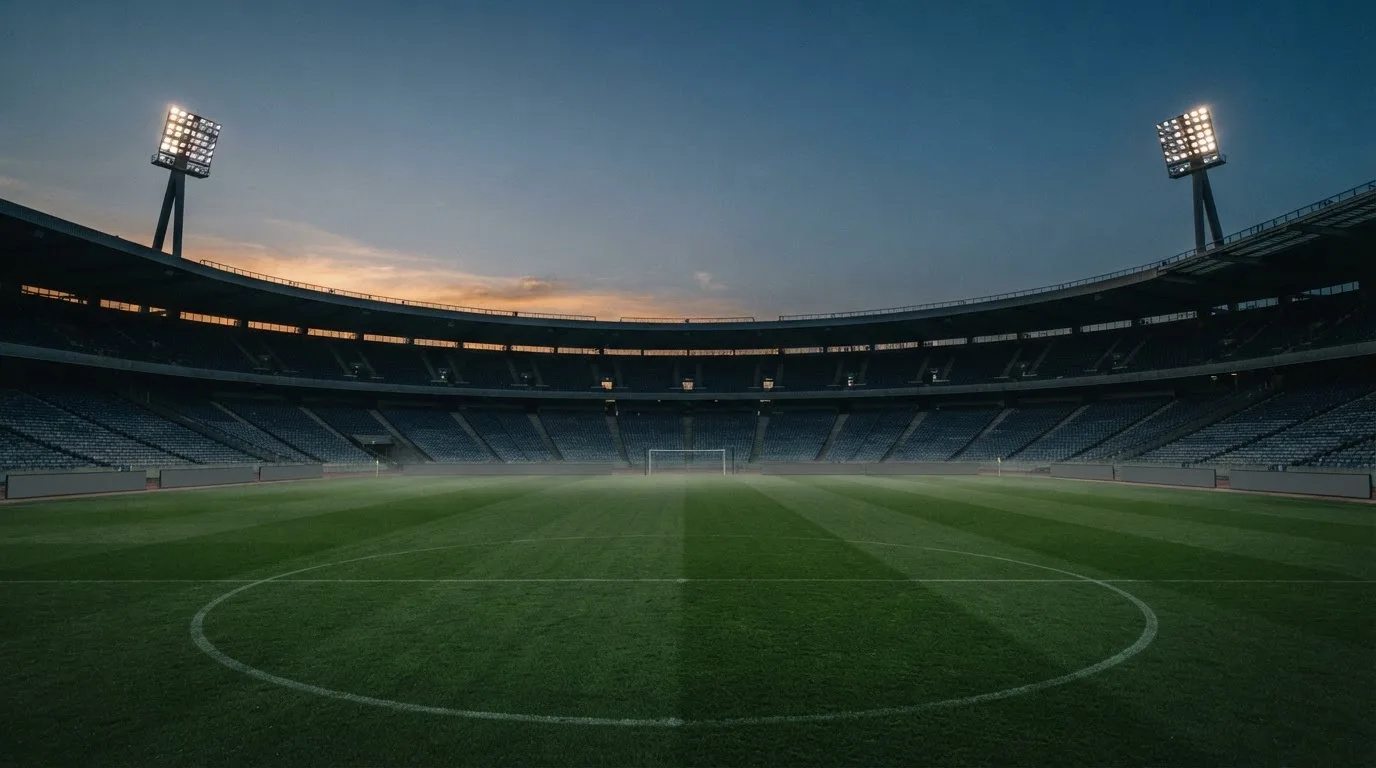 An empty football stadium with floodlight masts at dusk
