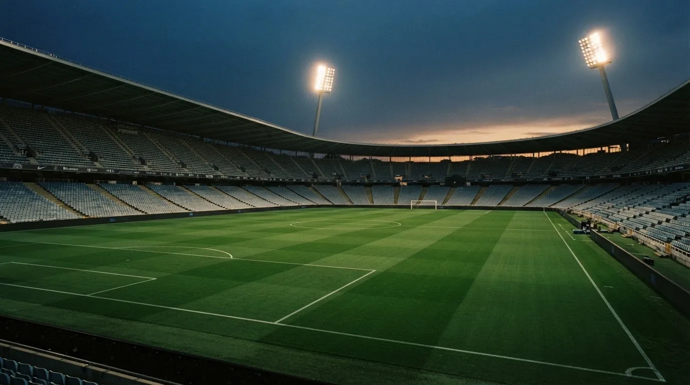 An empty football stadium with floodlight masts at dusk