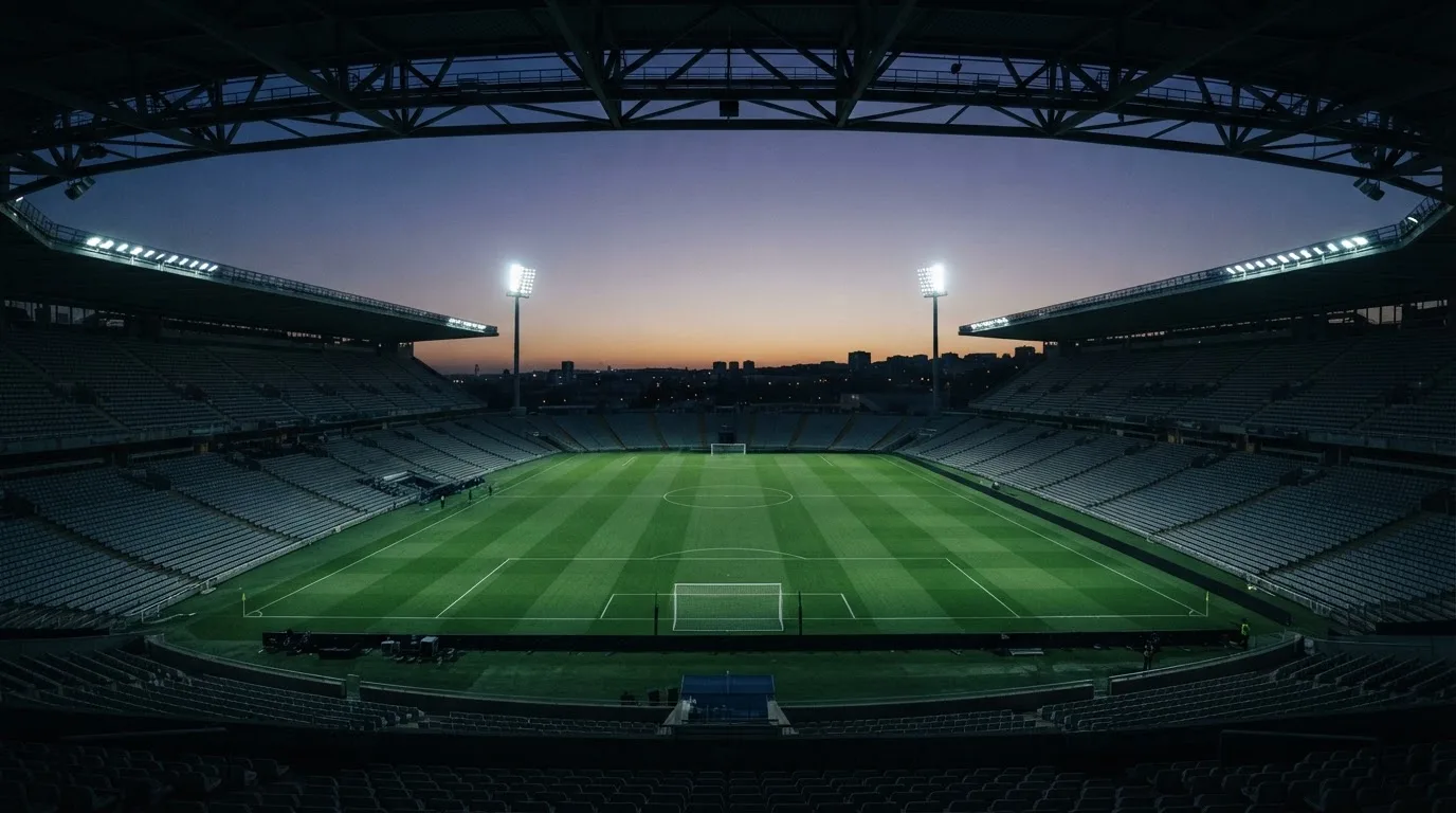 An empty football stadium with floodlight masts at dusk