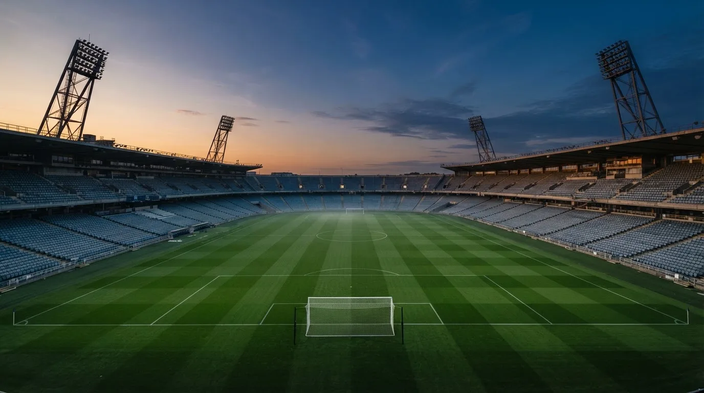 An empty football stadium with floodlight masts at dusk