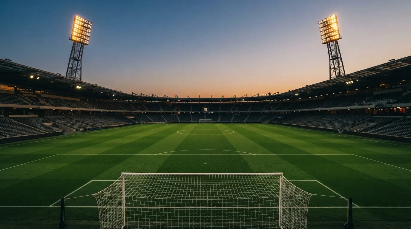 An empty football stadium with floodlight masts at dusk