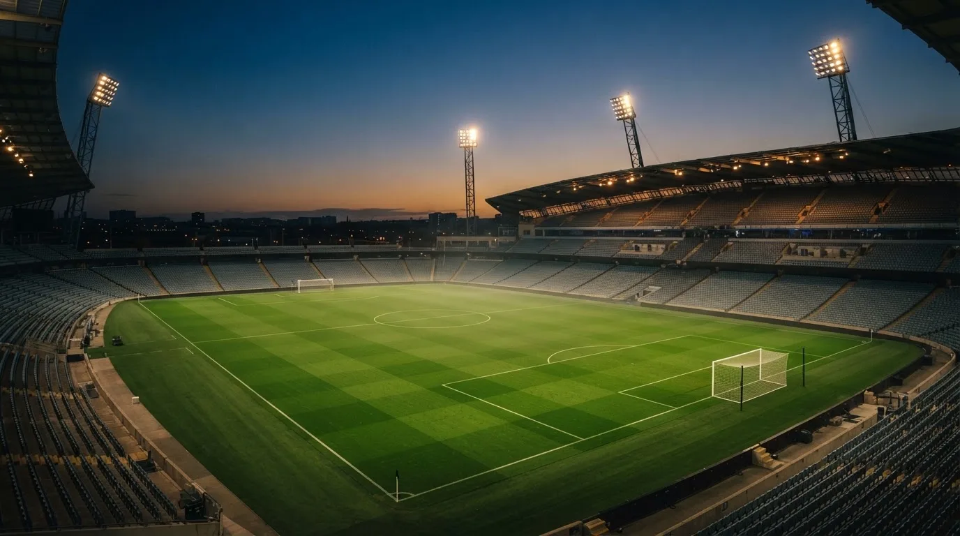 An empty football stadium with floodlight masts at dusk