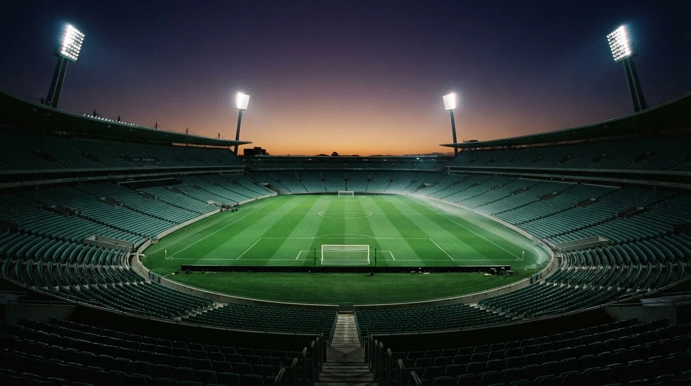 An empty football stadium with floodlight masts at dusk