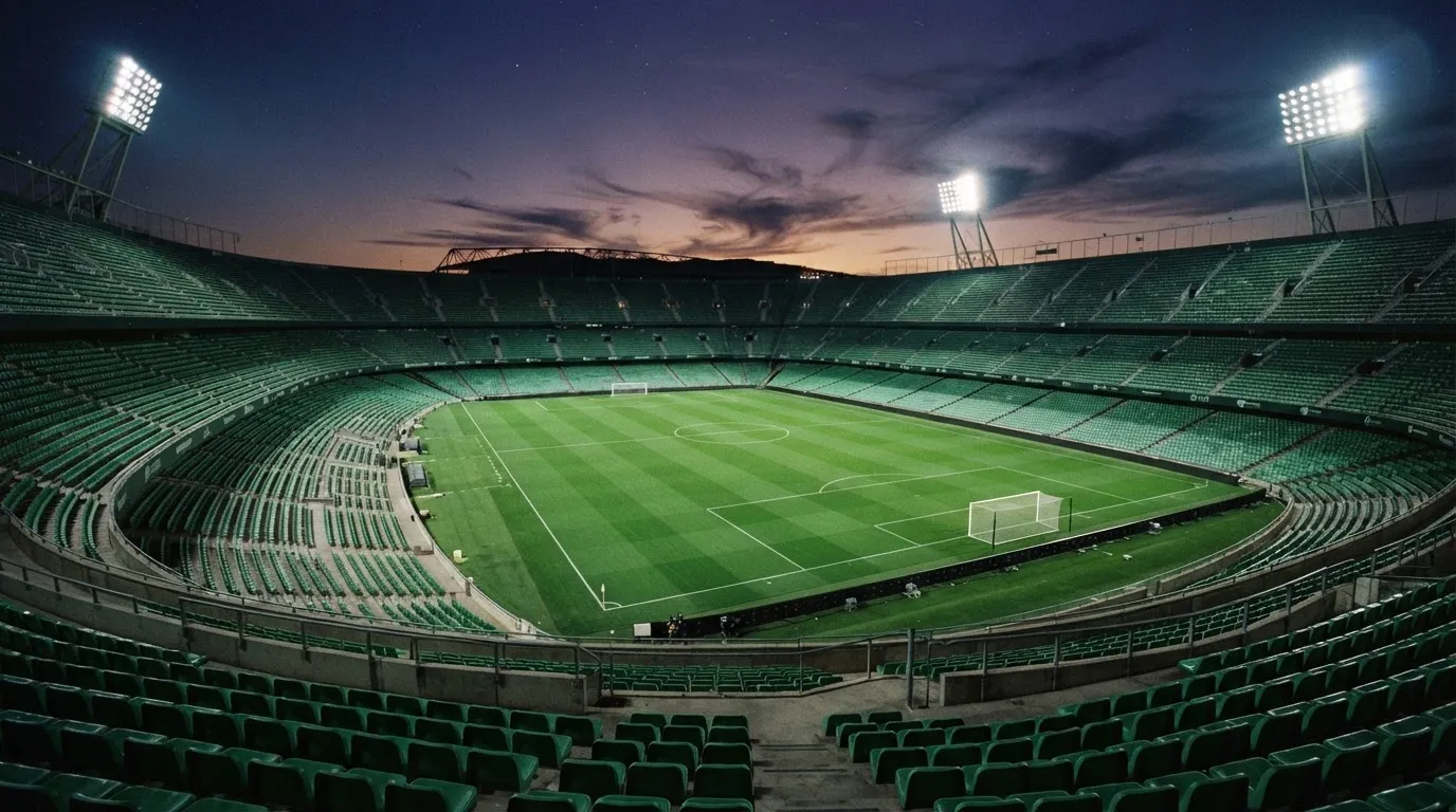 An empty football stadium with floodlight masts at dusk