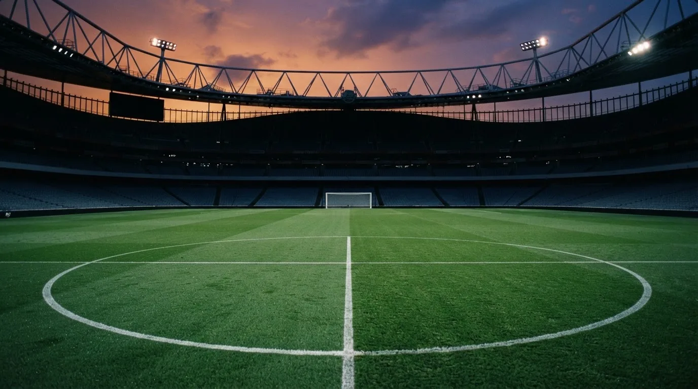 An empty football stadium with floodlight masts at dusk