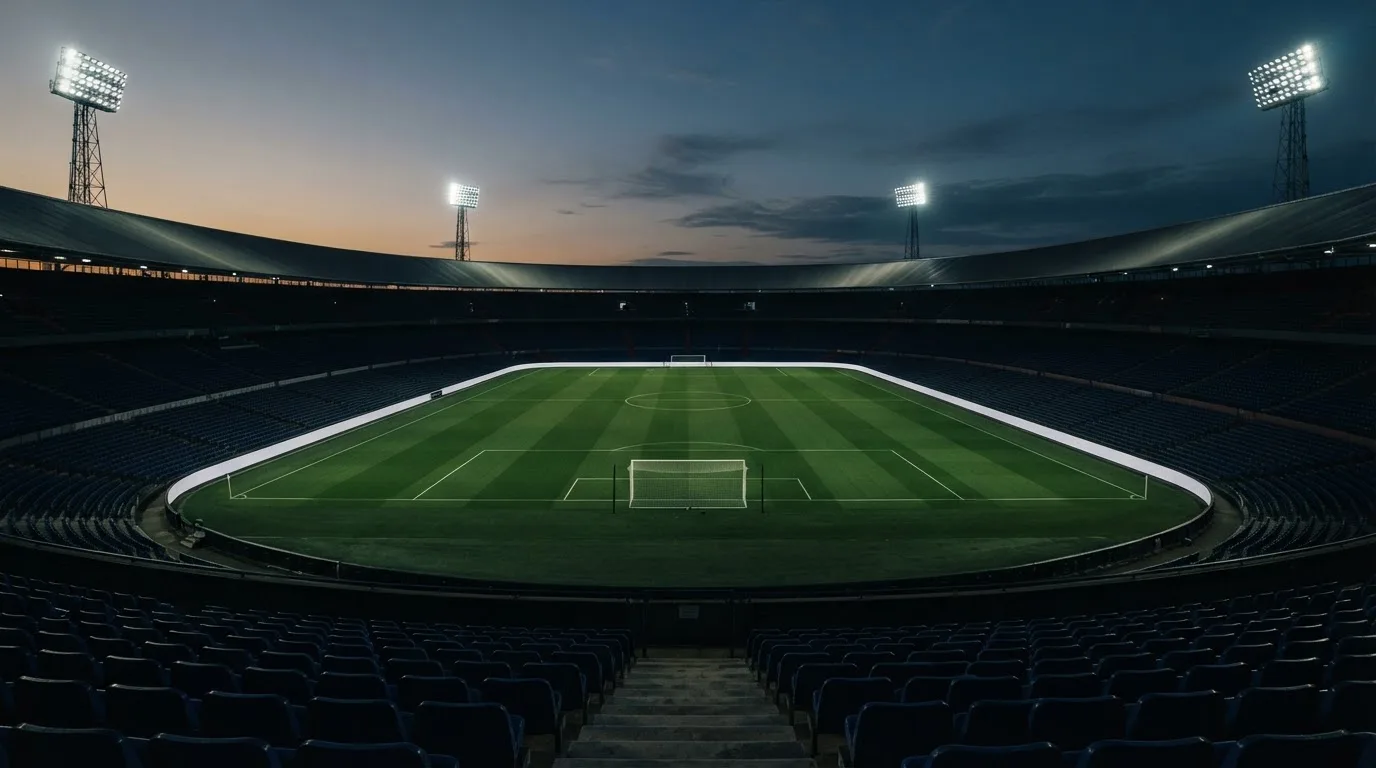 An empty football stadium with floodlight masts at dusk