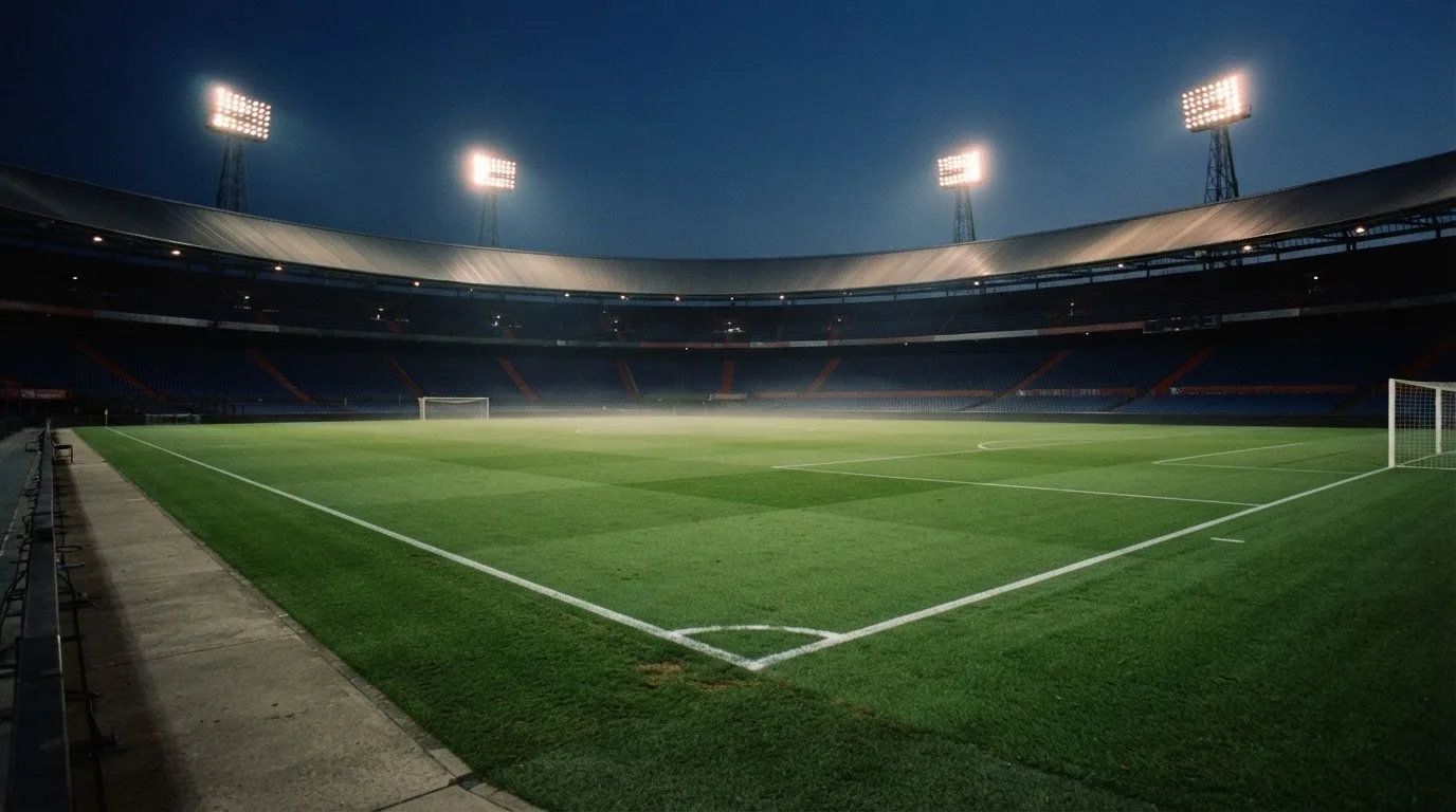 An empty football stadium with floodlight masts at dusk