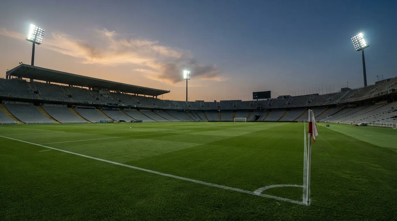 An empty football stadium with floodlight masts at dusk