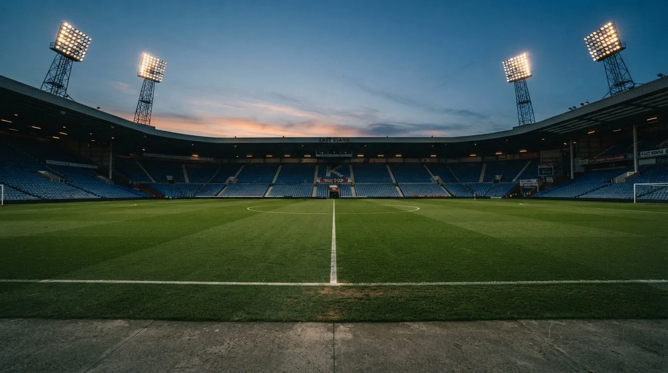 An empty football stadium with floodlight masts at dusk