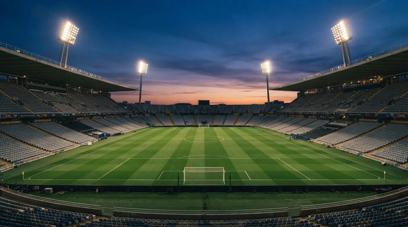 An empty football stadium with floodlight masts at dusk