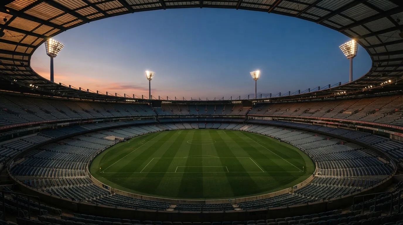 An empty football stadium with floodlight masts at dusk