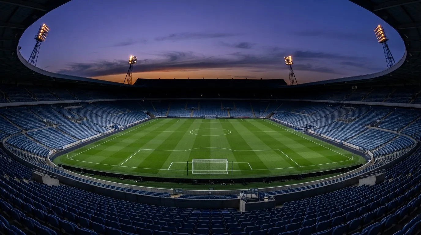 An empty football stadium with floodlight masts at dusk