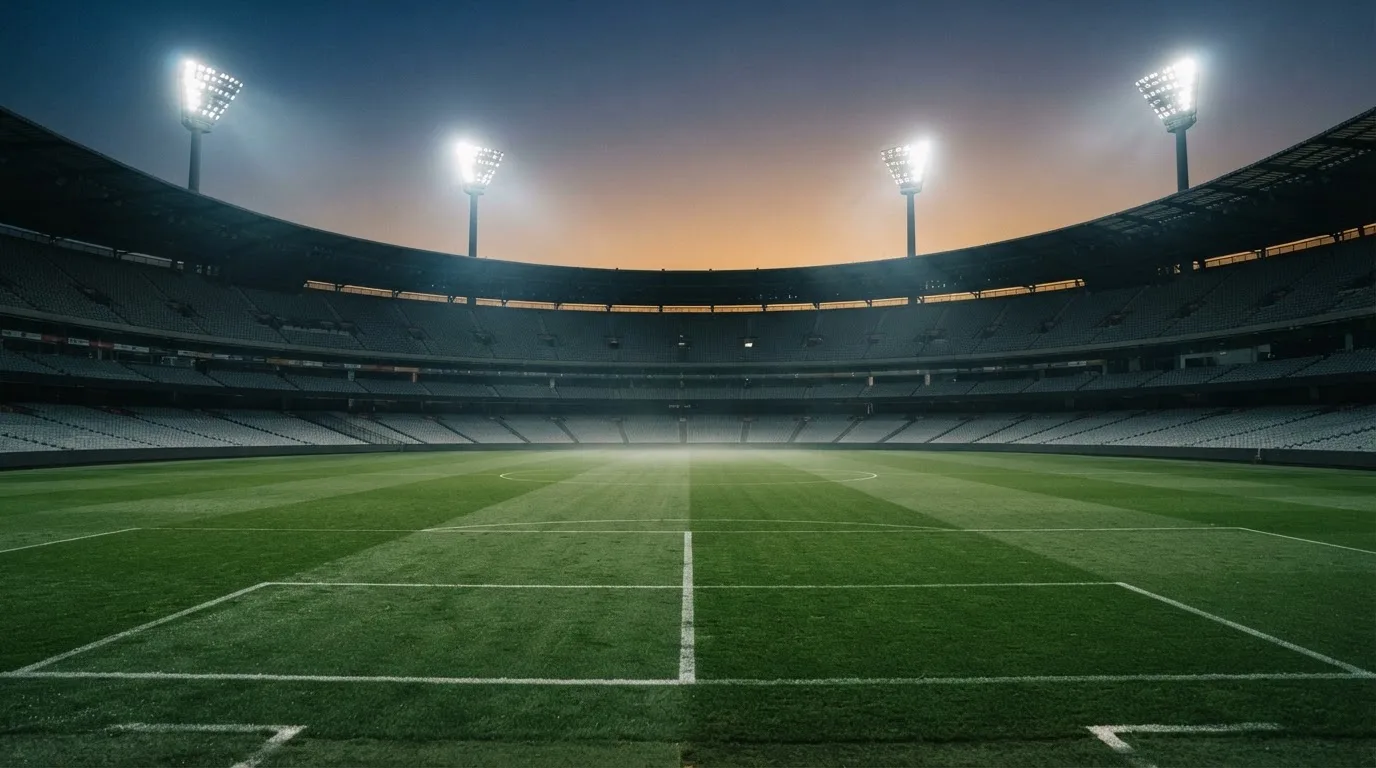 An empty football stadium with floodlight masts at dusk