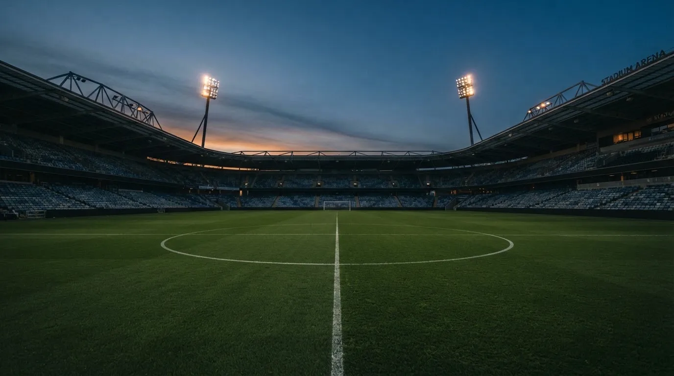 An empty football stadium with floodlight masts at dusk
