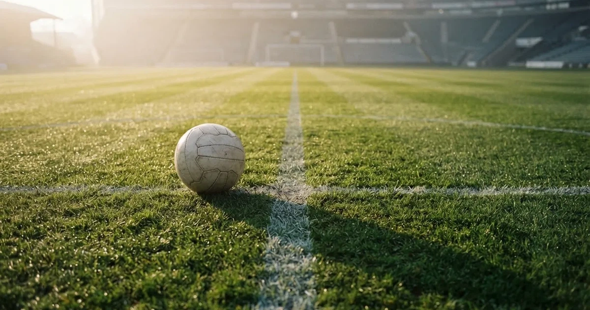 A ball on the centre spot of a grass pitch in morning light