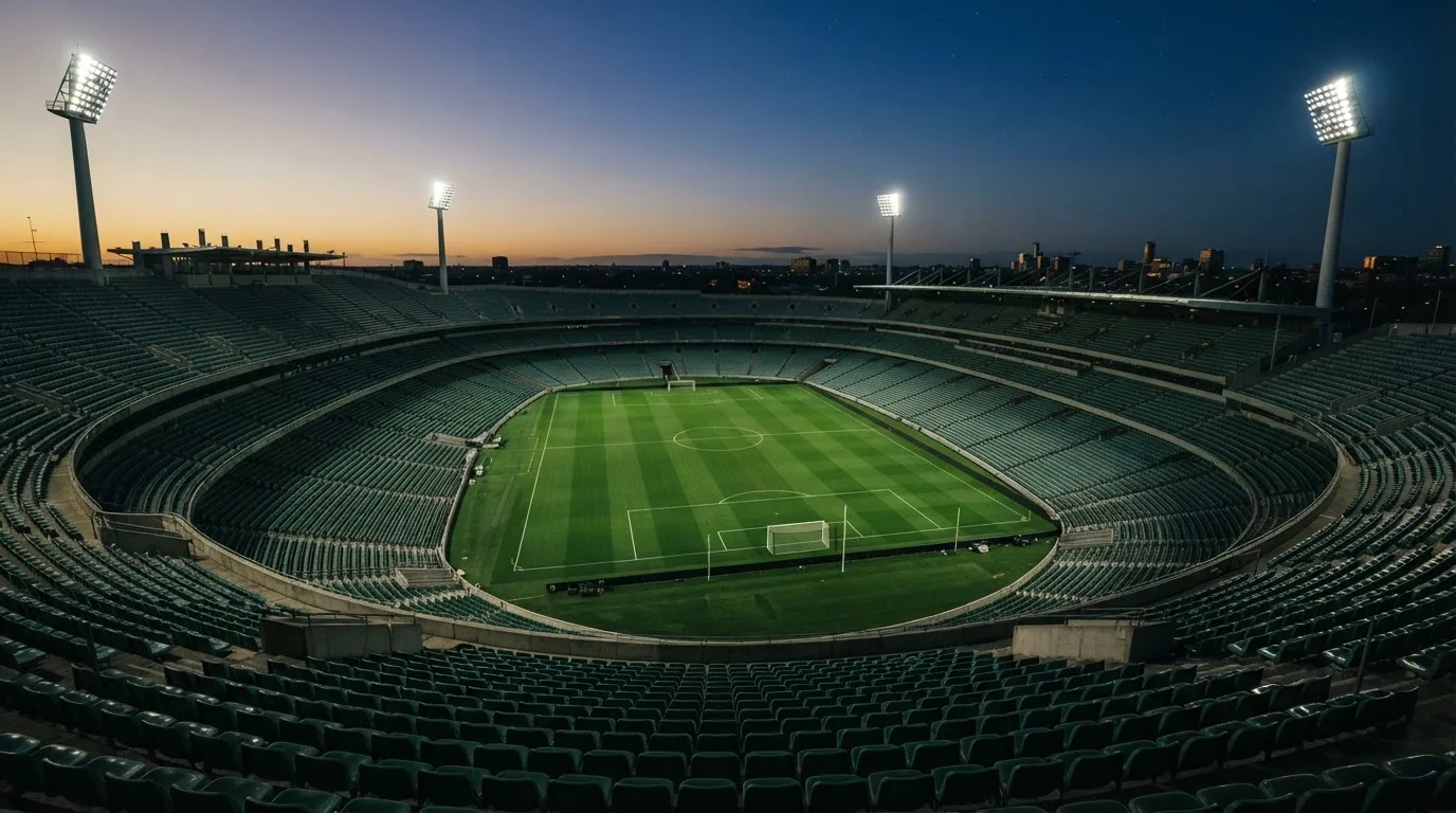 An empty football stadium with floodlight masts at dusk