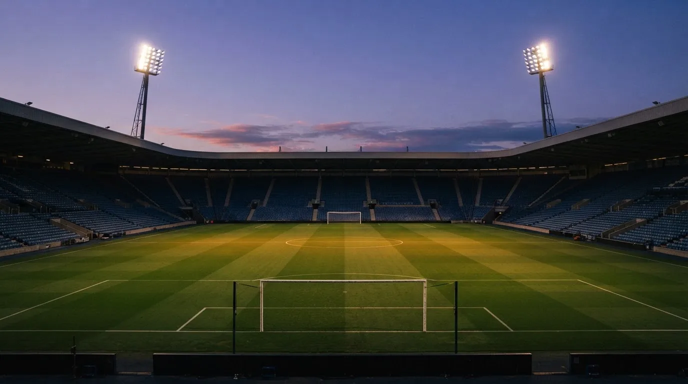 An empty football stadium with floodlight masts at dusk