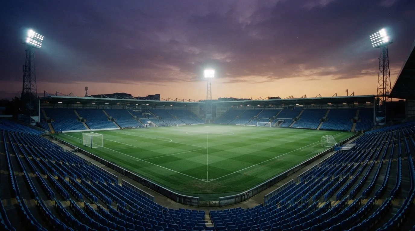 An empty football stadium with floodlight masts at dusk
