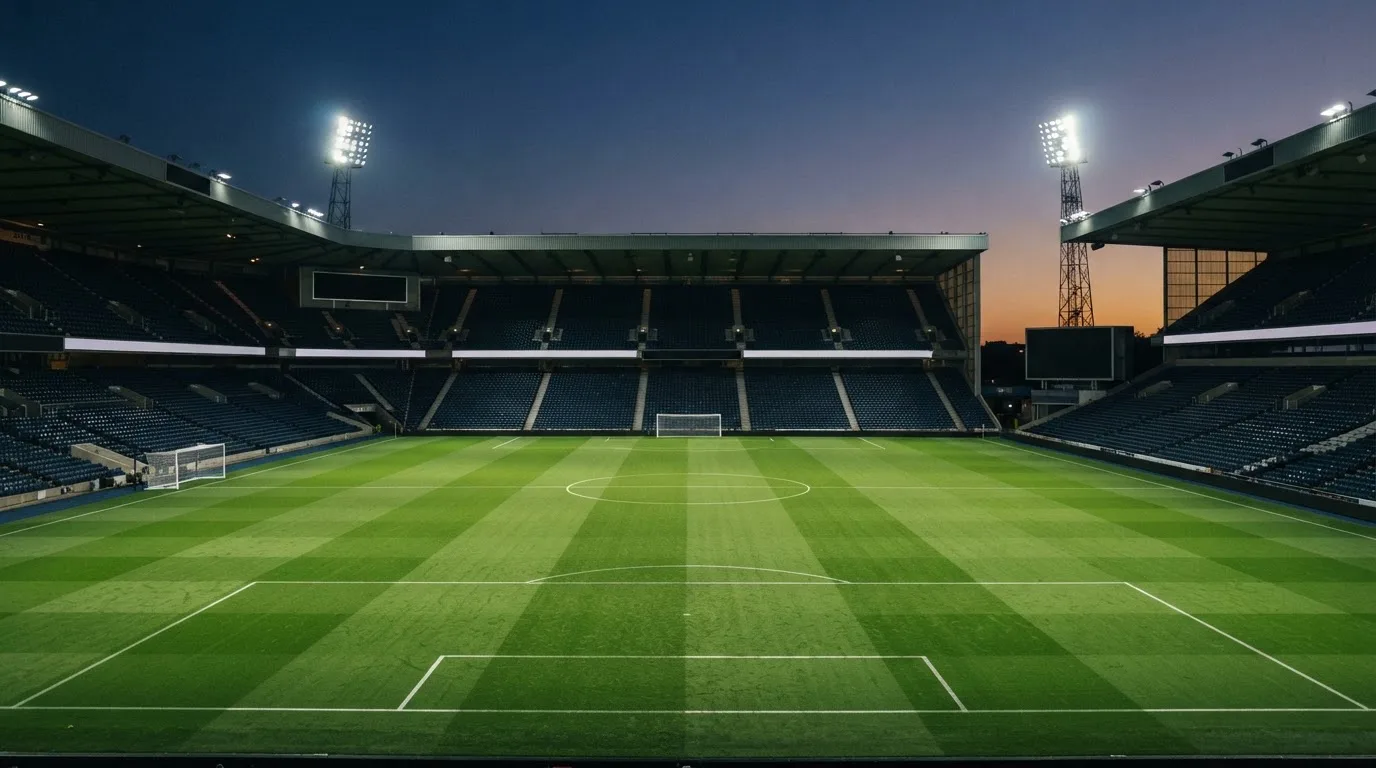 An empty football stadium with floodlight masts at dusk
