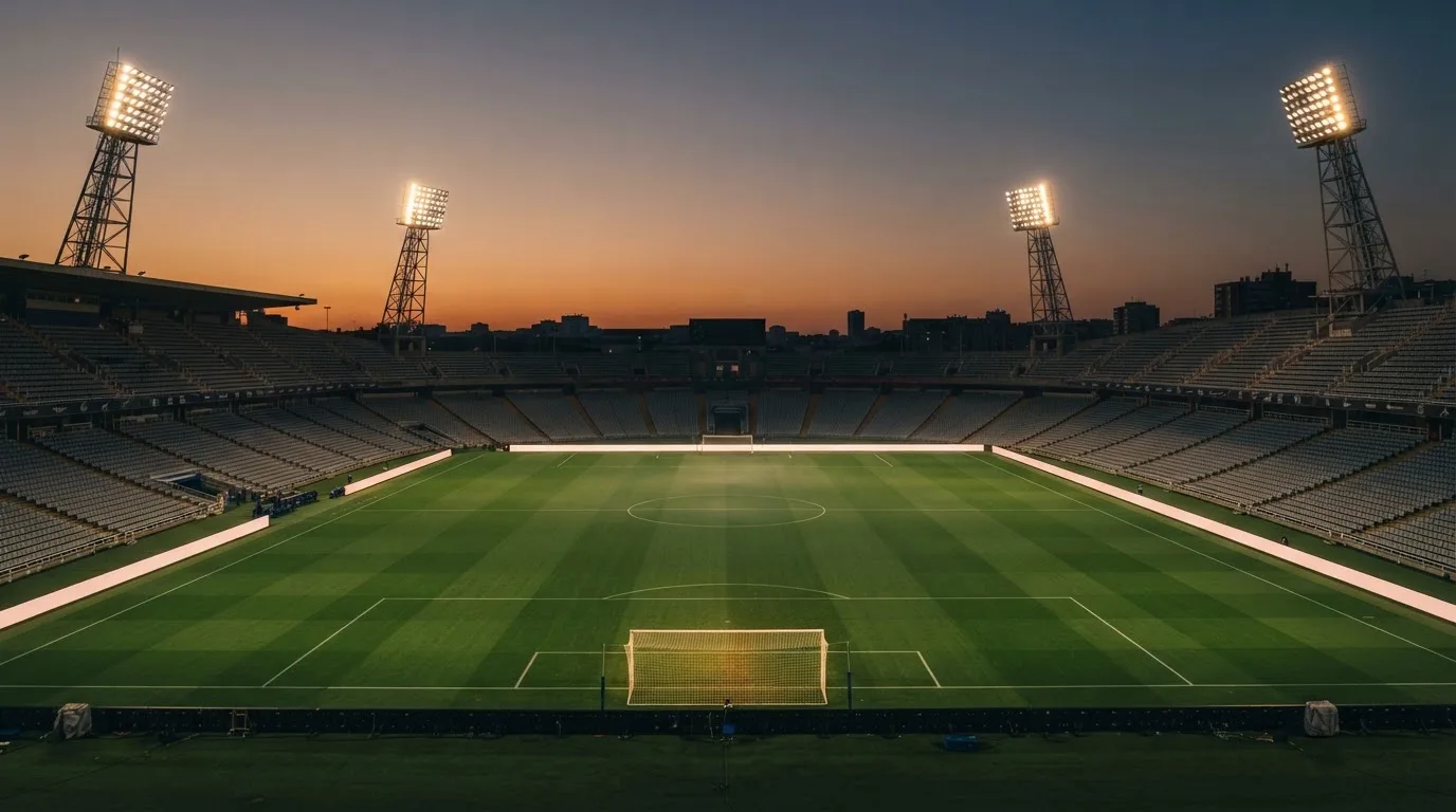 An empty football stadium with floodlight masts at dusk