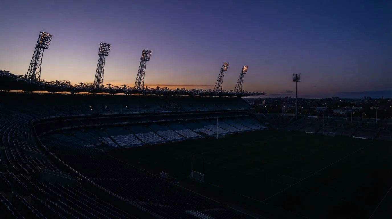 An empty football stadium with floodlight masts at dusk