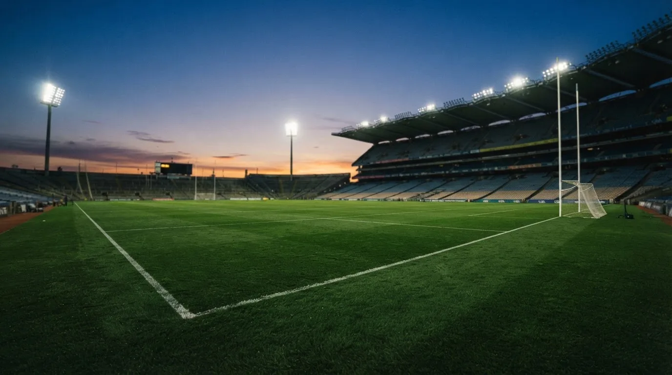 An empty football stadium with floodlight masts at dusk