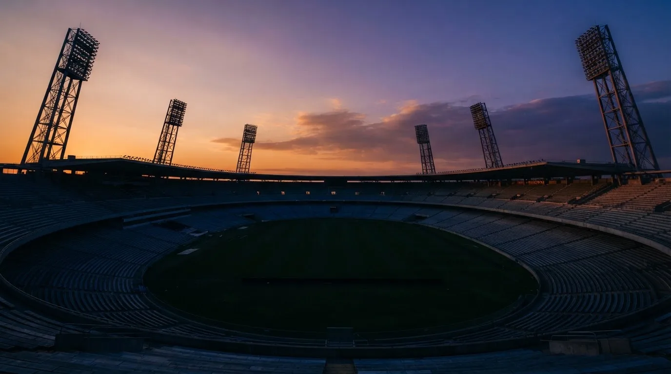 An empty football stadium with floodlight masts at dusk