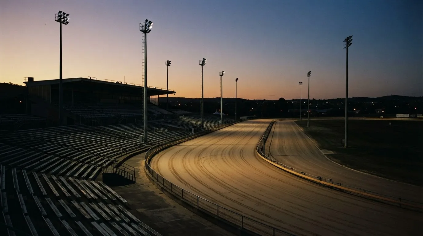 An empty football stadium with floodlight masts at dusk