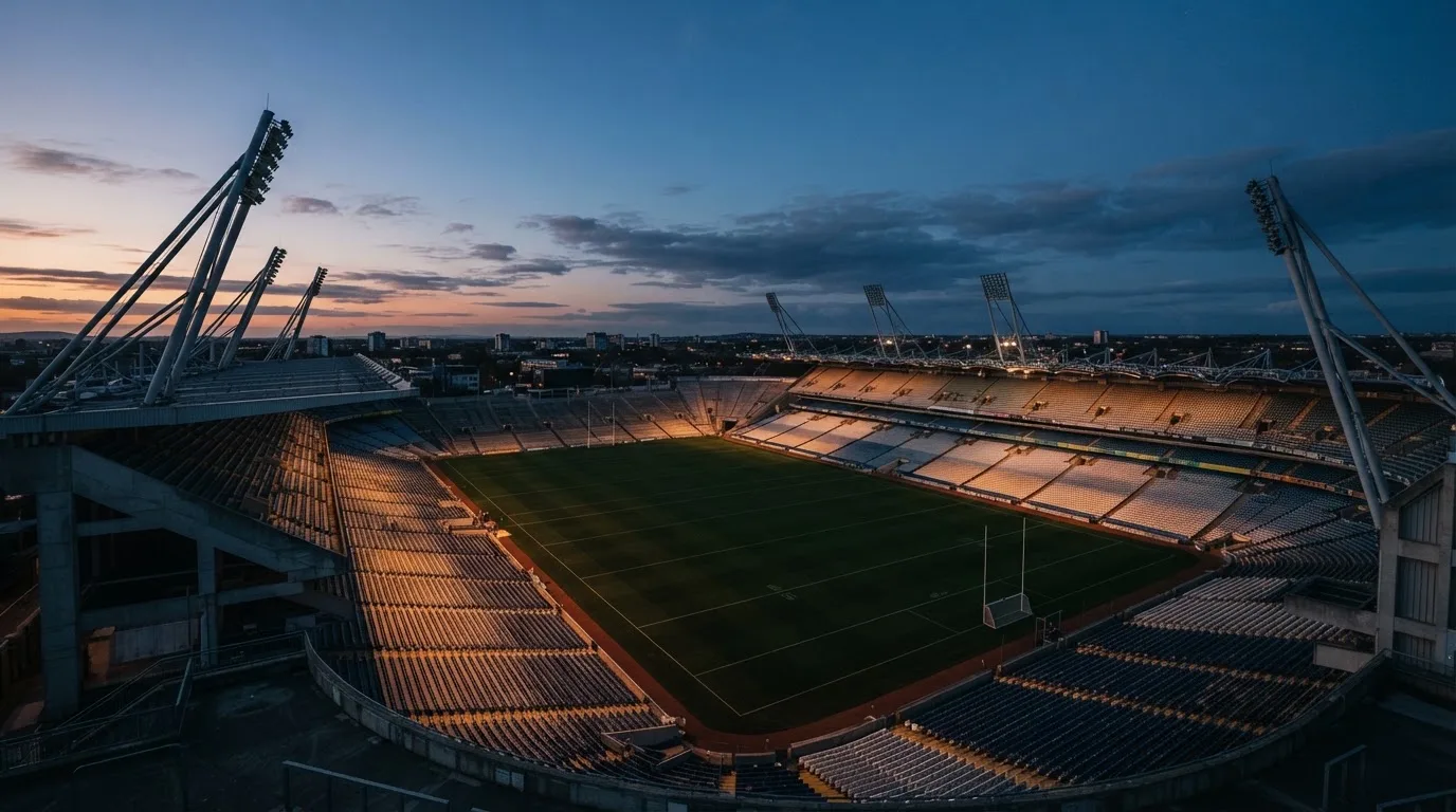 An empty football stadium with floodlight masts at dusk