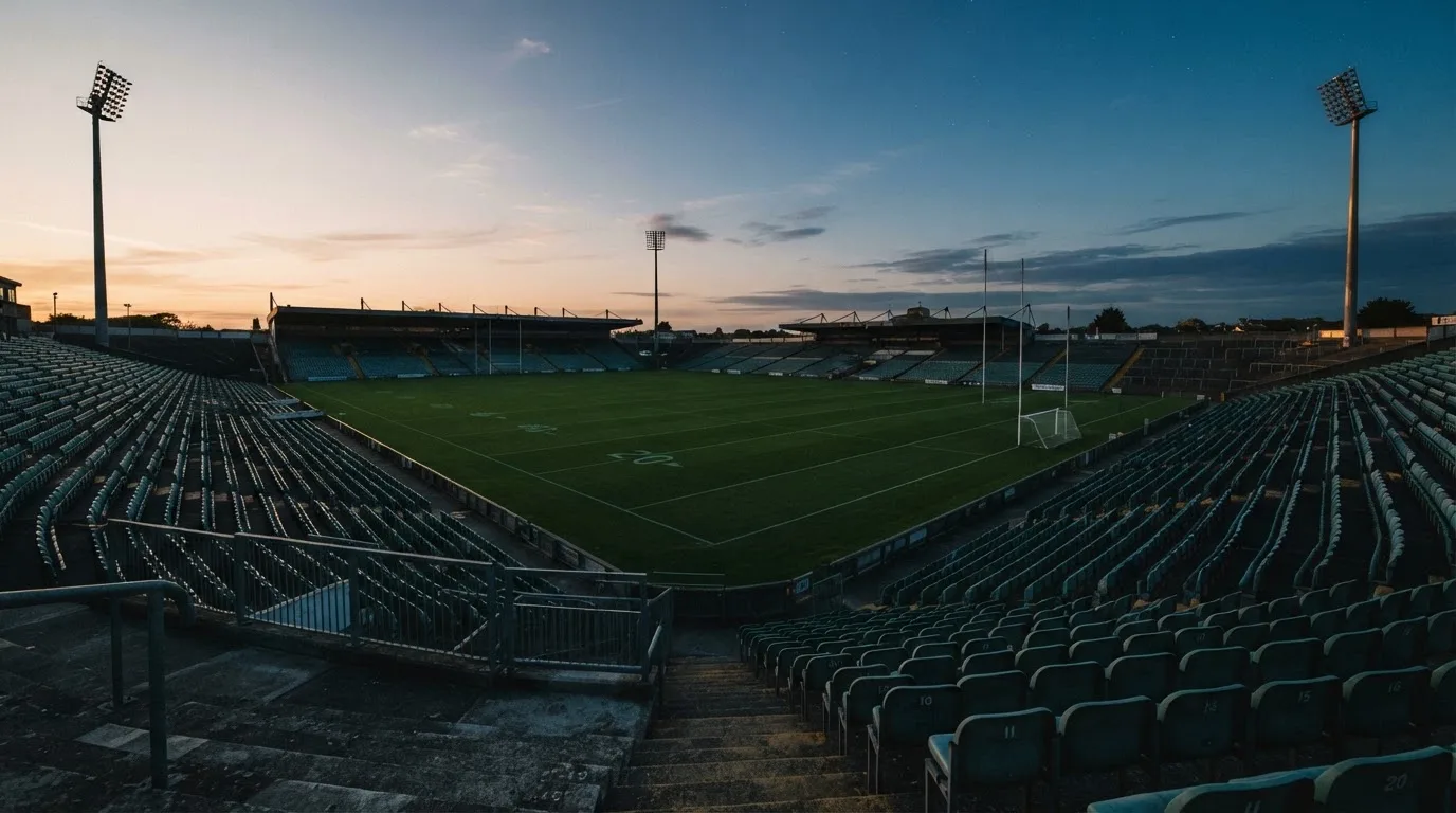 An empty football stadium with floodlight masts at dusk