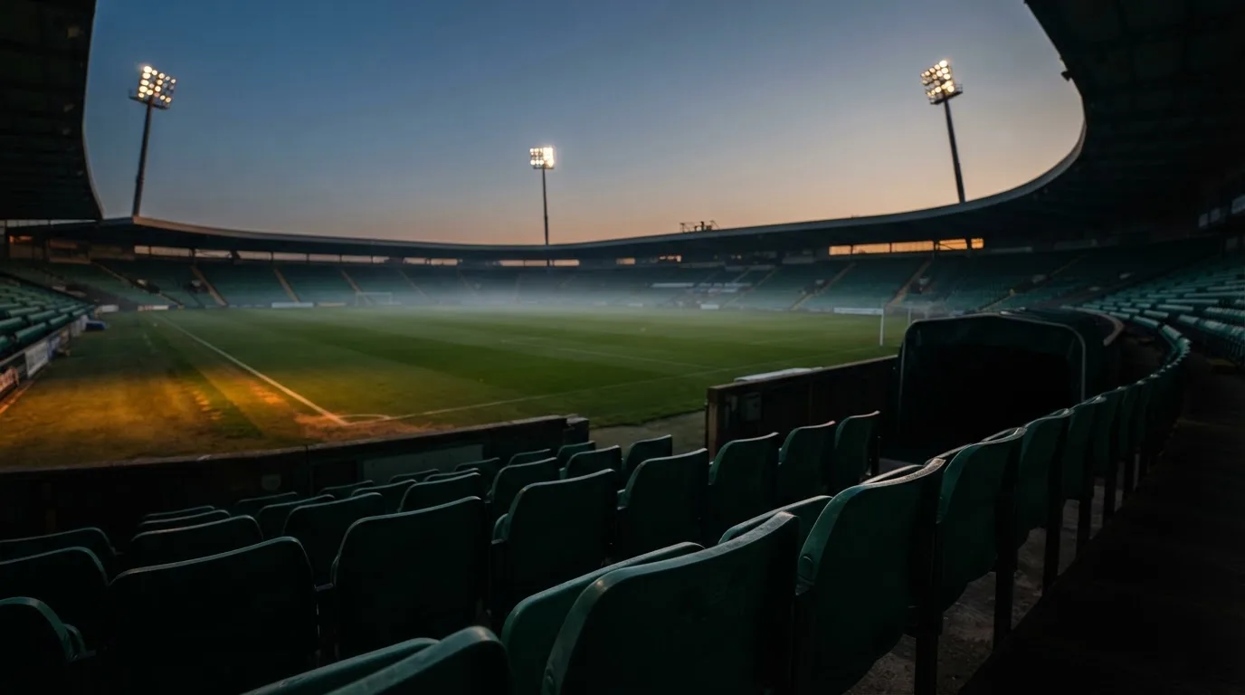 An empty football stadium with floodlight masts at dusk