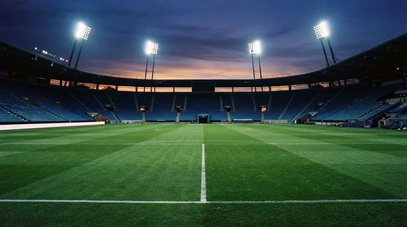An empty football stadium with floodlight masts at dusk