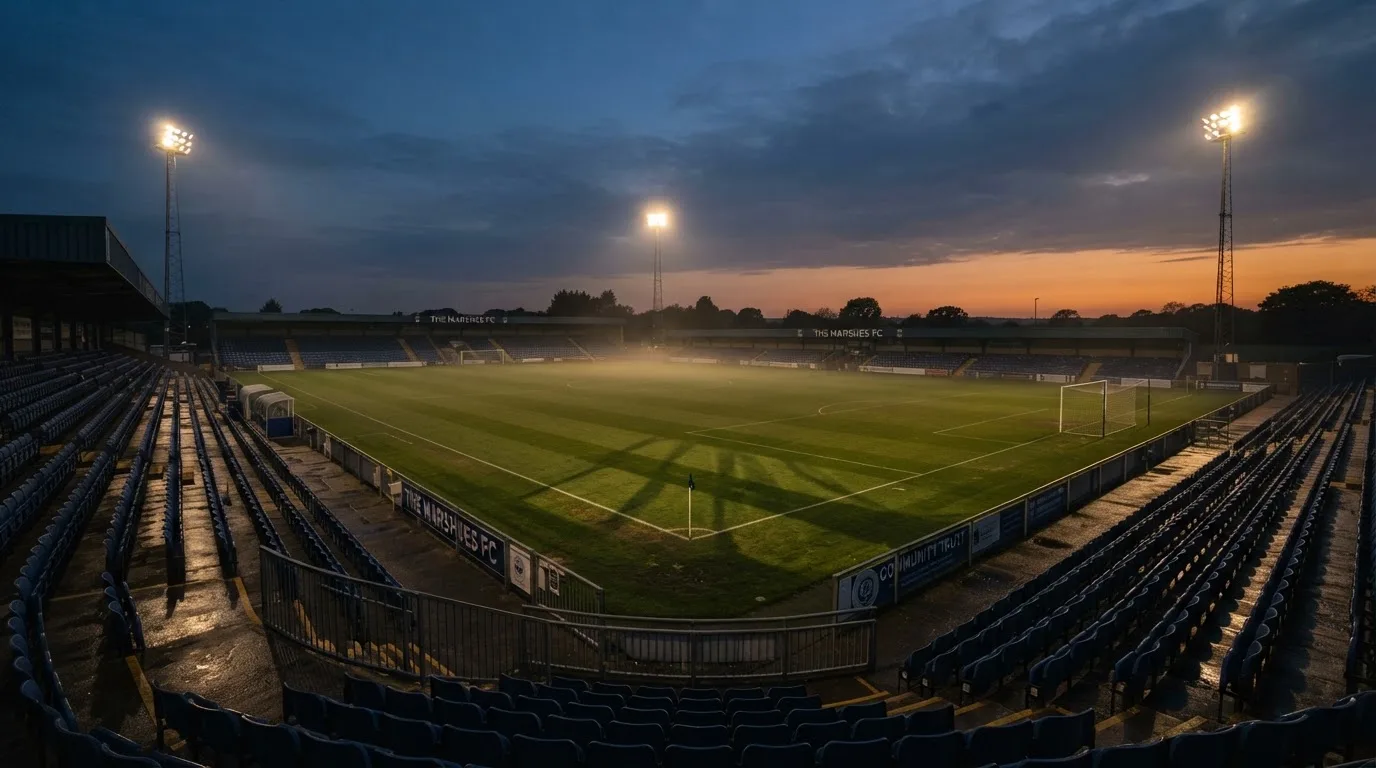 An empty football stadium with floodlight masts at dusk