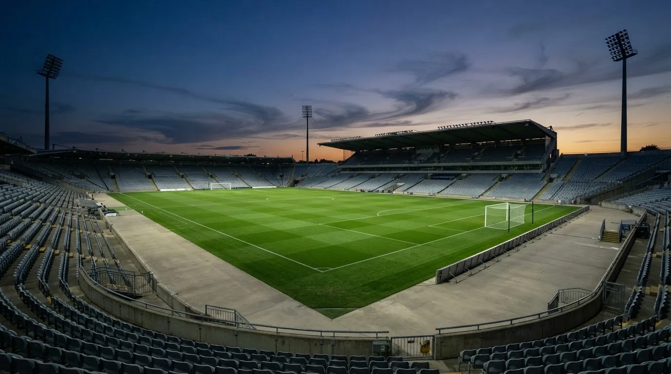 An empty football stadium with floodlight masts at dusk