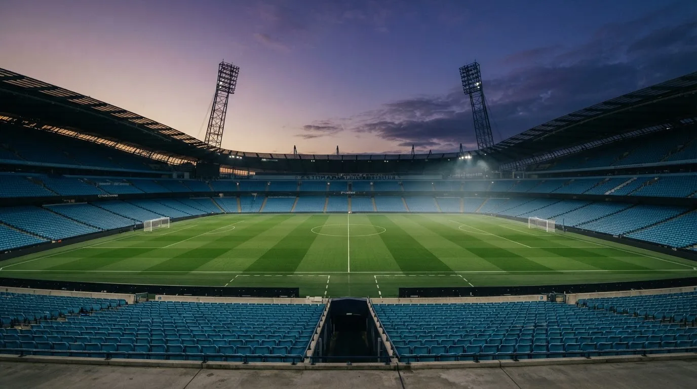 An empty football stadium with floodlight masts at dusk
