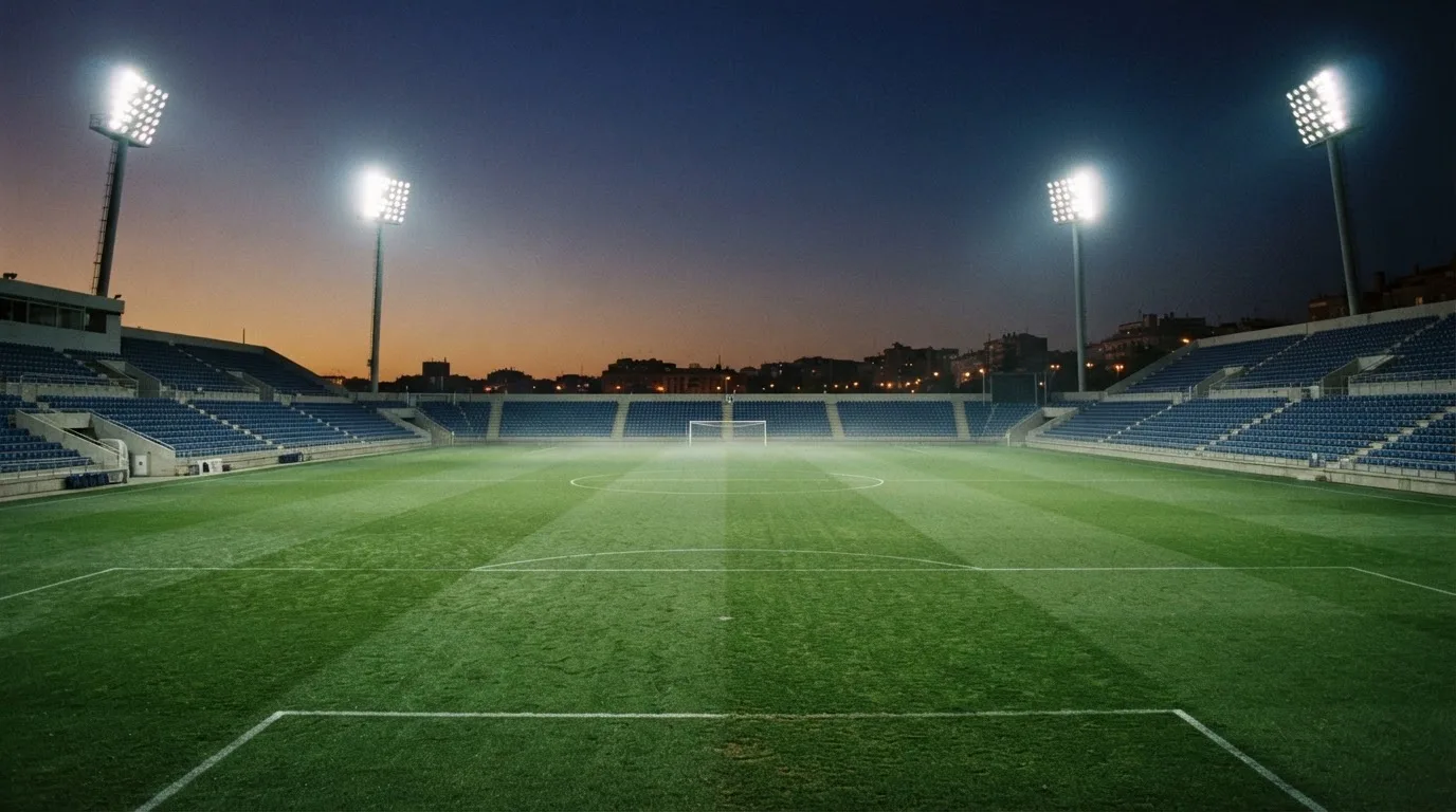 An empty football stadium with floodlight masts at dusk