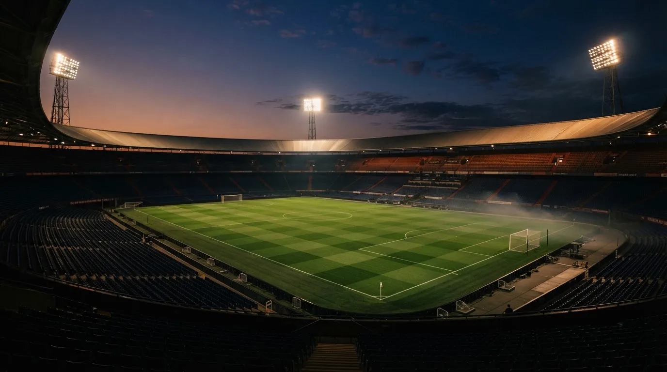 An empty football stadium with floodlight masts at dusk