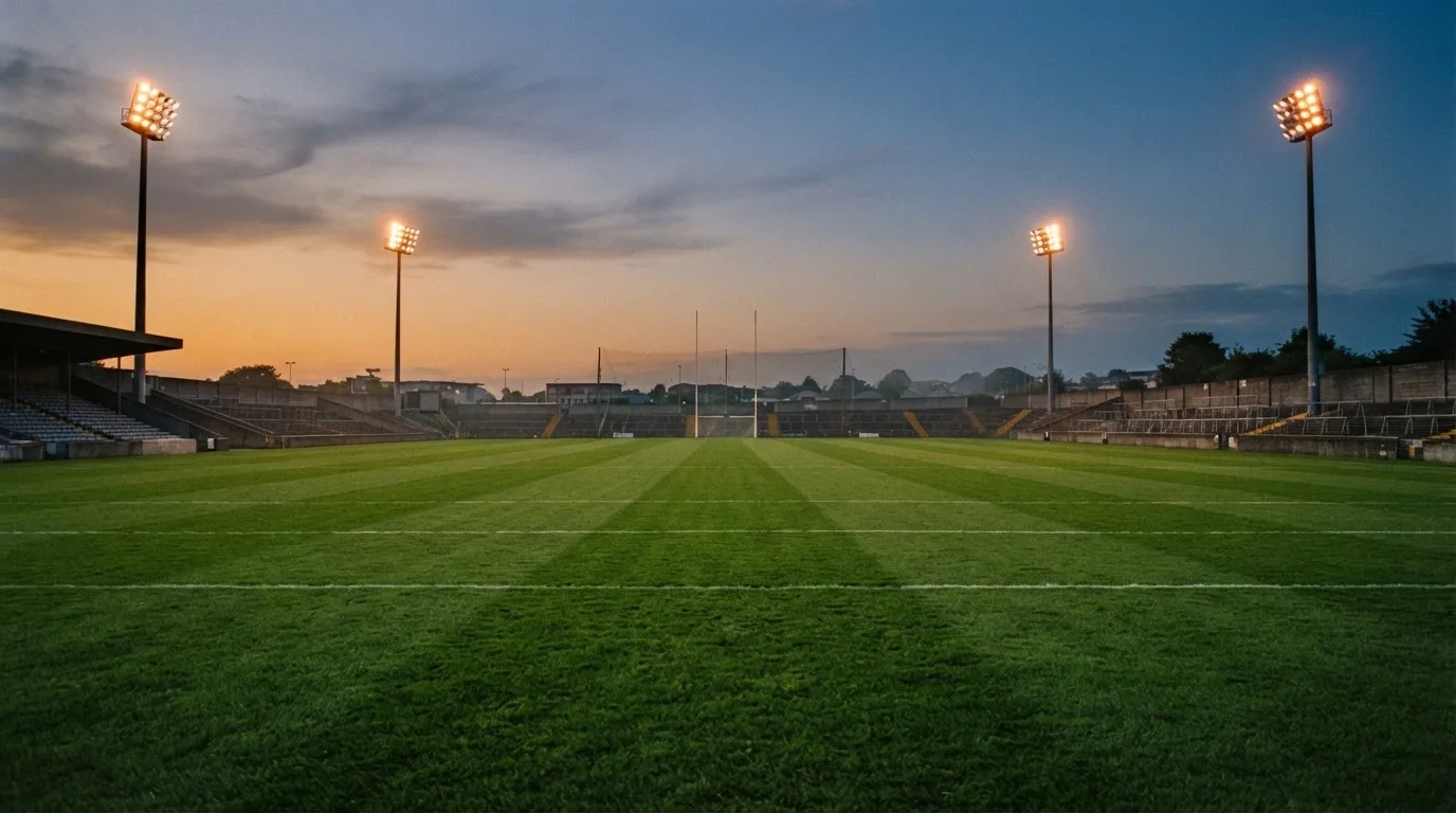 An empty football stadium with floodlight masts at dusk