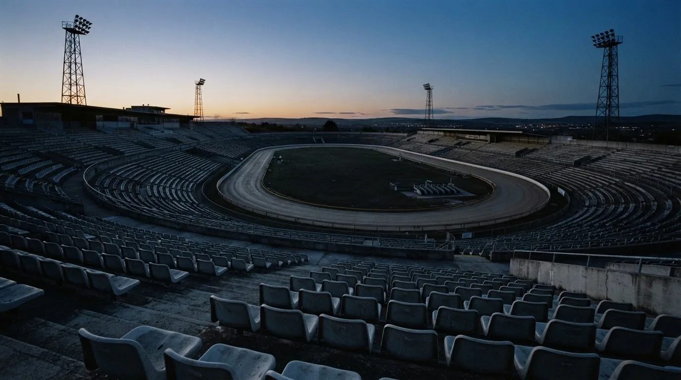An empty football stadium with floodlight masts at dusk